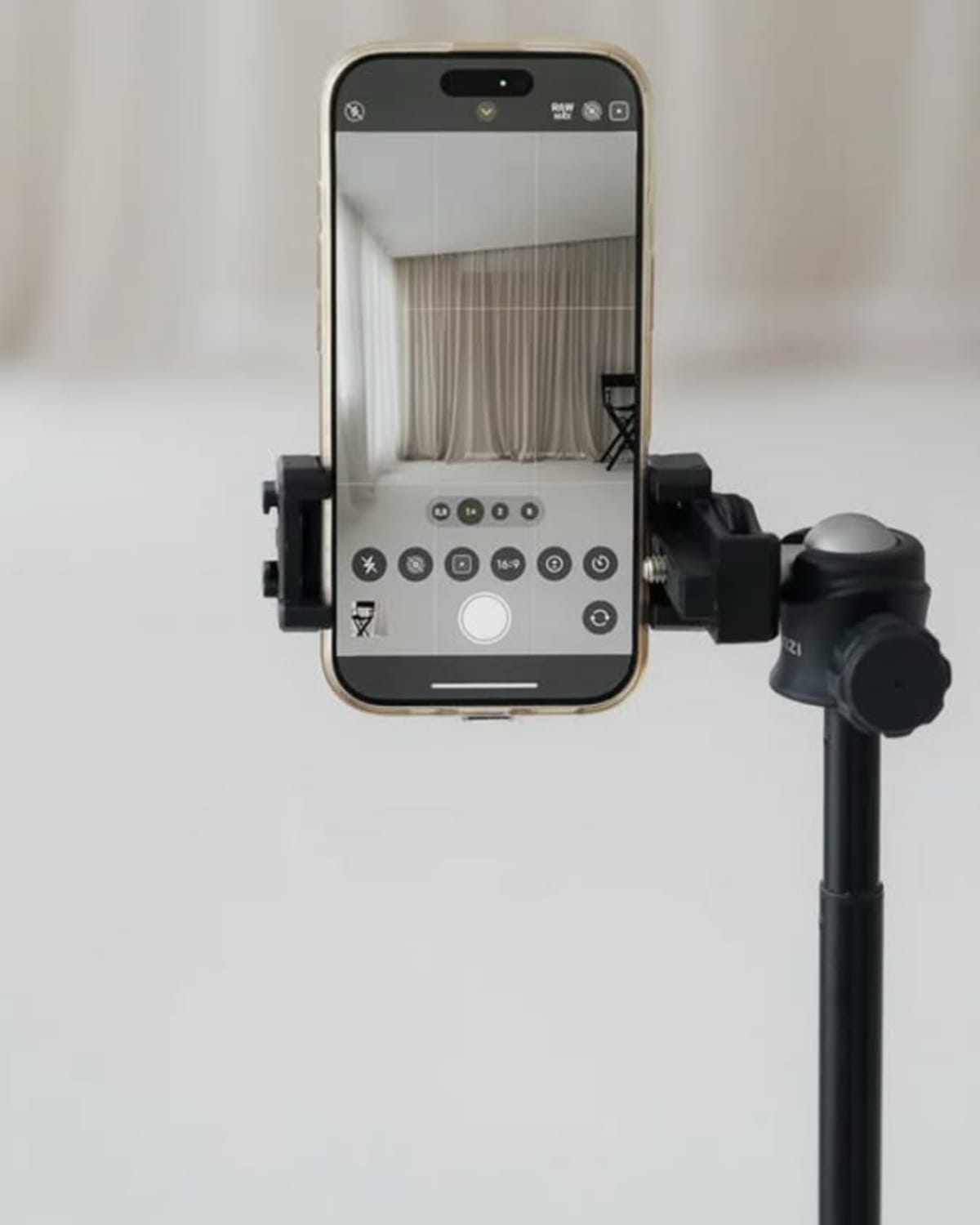 Téléphone monté sur trépied filmant un décor avec rideaux, pour du contenu créateur.