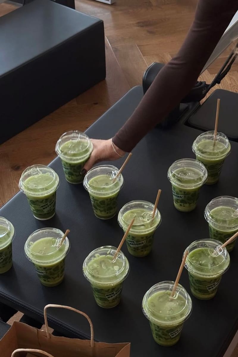 Rangée de boissons vertes glacées avec pailles, posées sur un banc.