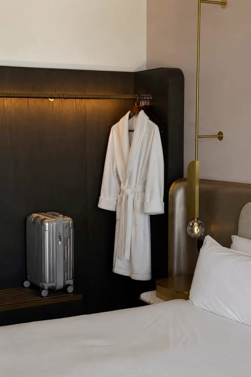 Peignoir suspendu près d'une valise, dans une chambre d'hôtel feutrée.