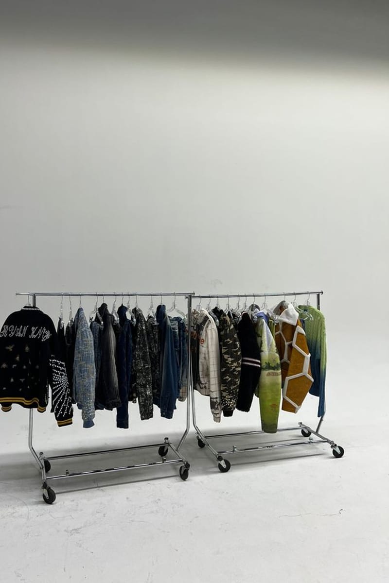 Portants de vêtements alignés sur fond gris studio.